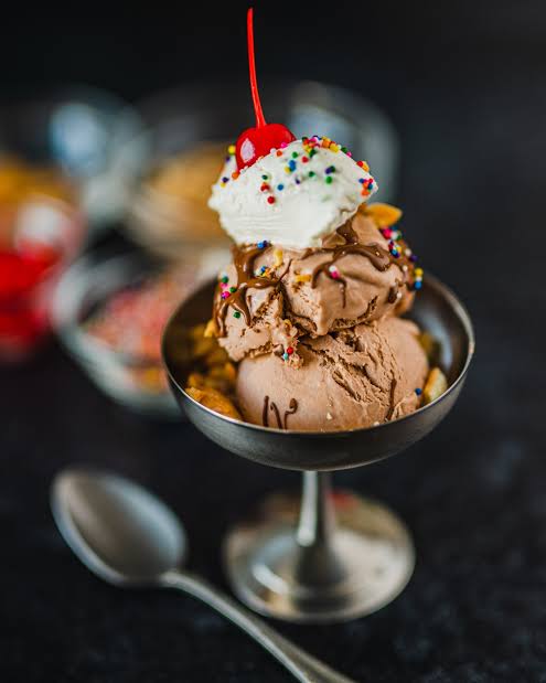 A rich chocolate ice cream scoop with cherry and sprinkles